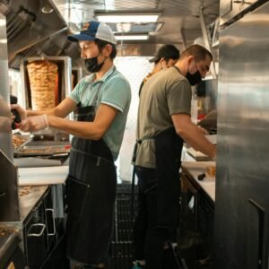 Chefs working in a food truck preparing delicious street food for customers.