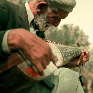 Elderly man outdoors playing a traditional instrument in Islamabad, Pakistan, showcasing cultural heritage.